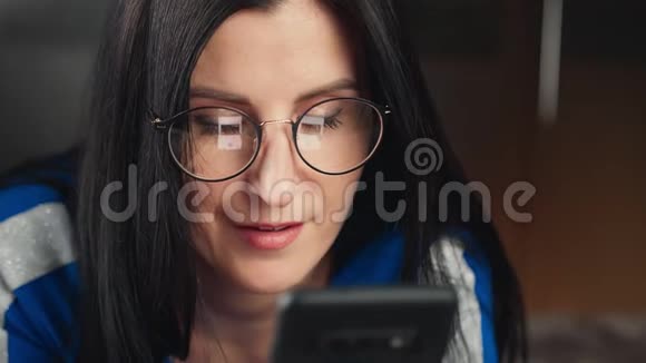 特写戴眼镜的可爱女孩看着智能手机屏幕4k龙红色摄像机视频的预览图