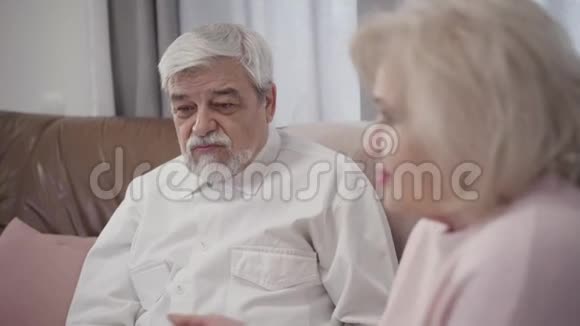 白种人白发老人与妻子在家交谈的特写镜头已婚退休人员在室内休息视频的预览图