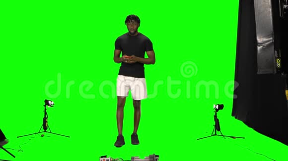 一位美国黑人男子正在绿色屏幕上用手机边走边发短信正面视频的预览图
