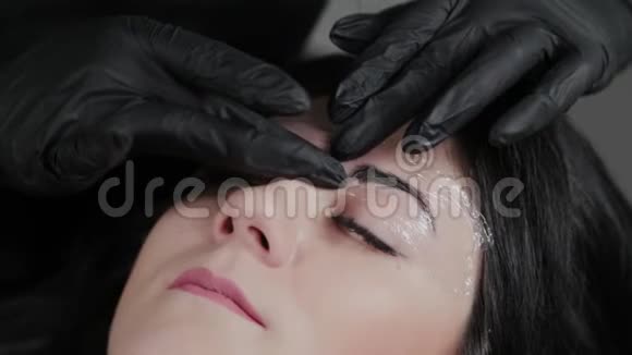 一位专业的永久性化妆大师用胶卷遮住客户的眉毛视频的预览图