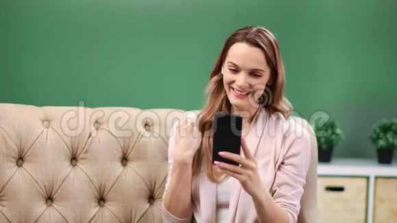兴奋的金发女郎看着智能手机做着胜利的手势4k龙红色摄像机视频的预览图