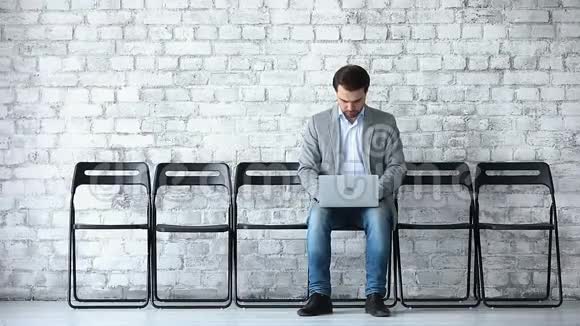 商务申请人在候诊室使用笔记本电脑坐在椅子上视频的预览图