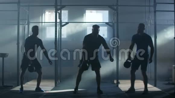 慢速运动三名运动员在一个大气健身室中在阳光的背景下举重视频的预览图