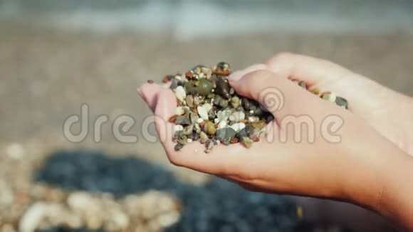 女性的手拿着一把湿鹅卵石在海上休息冥想概念视频的预览图