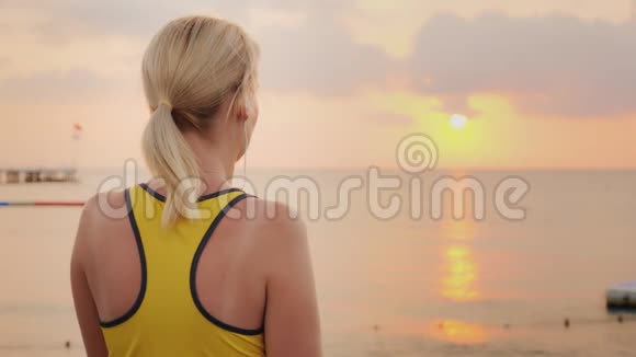 活跃的女人在运动后喝干净的水在大海的背景下太阳升起视频的预览图