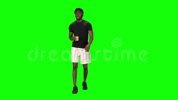 一位非洲裔美国人正在绿屏边散步边喝咖啡正视图视频的预览图
