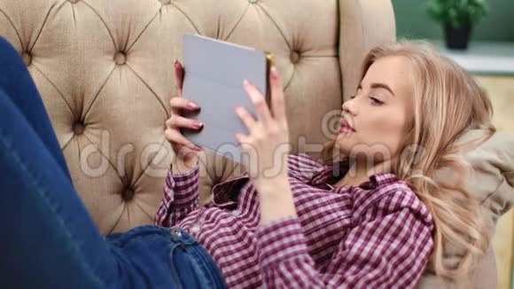放松的女人躺在沙发上用平板电脑享受周末4k红色摄像机特写镜头视频的预览图
