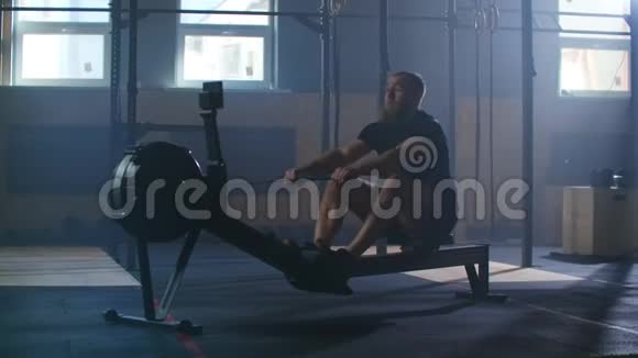 慢动作划艇训练有氧运动训练一个男人在阳光下划船在一个大气的健身室里视频的预览图