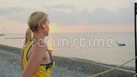 健身妇女在清晨慢跑在大海的背景下太阳升起视频的预览图
