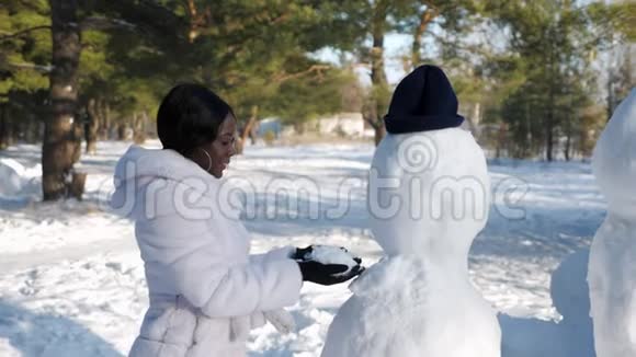 非洲裔美国妇女在冬天的大自然中堆雪人视频的预览图