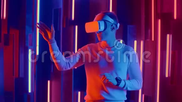 未来的虚拟现实一个戴着头盔和霓虹灯的人在虚拟现实中移动双手视频的预览图
