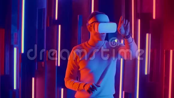 未来的虚拟现实一个戴着头盔和霓虹灯的人在虚拟现实中移动双手视频的预览图