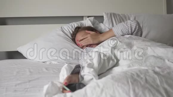 女人早上在床上醒来用手机看时间视频的预览图
