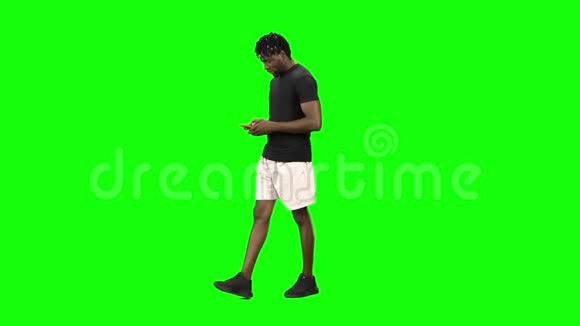 非裔美国人走路和发短信给他的手机在绿色屏幕Chroma键视频的预览图
