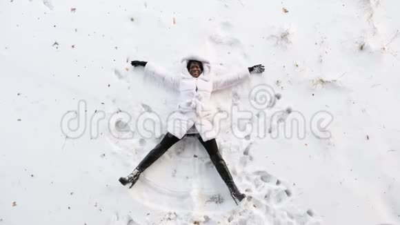 黑女孩躺在白色的林间空地上做雪角视频的预览图