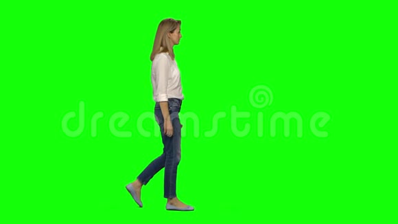 金发女郎在绿色屏幕上平静地走着用手机聊天彩色键4k镜头纵断面图视频的预览图