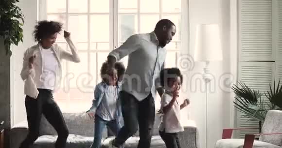 快乐的非洲夫妇和学龄前儿童在客厅跳舞视频的预览图