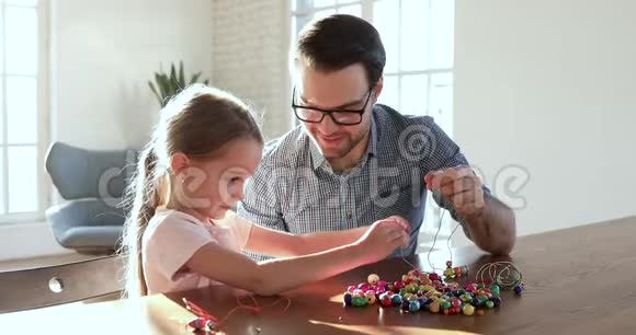 可爱的父亲帮助小女儿串珠项链视频的预览图