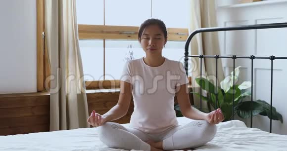 健康的亚洲女孩闭着眼睛在床上冥想视频的预览图