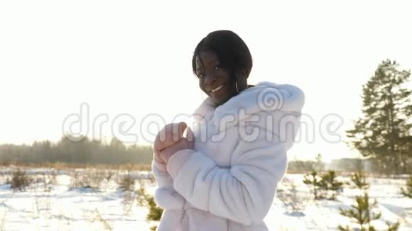 微笑的黑皮肤女孩在空旷的雪地上摆姿势视频的预览图