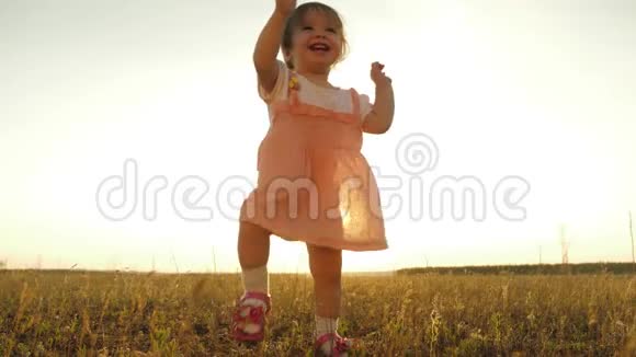 小女儿走向父母微笑慢动作快乐的孩子在公园日落时迈出第一步视频的预览图