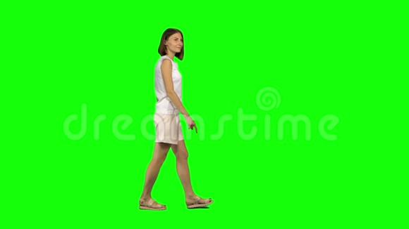 一位棕色头发头发光滑的年轻女子正平静地走在绿色的屏幕上彩色键4k镜头纵断面图视频的预览图