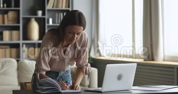 年轻的女企业家用手提笔记立在桌子上视频的预览图