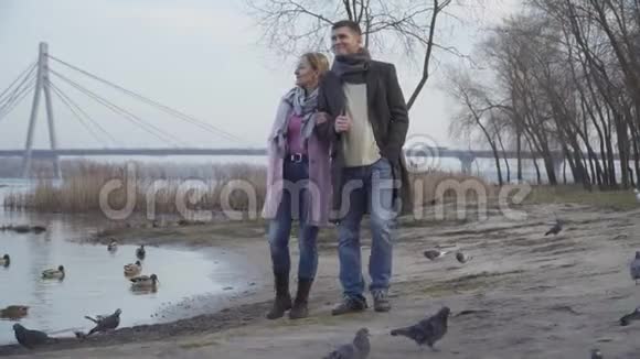 白种人成年夫妇沿着河岸散步离开的肖像鸭子从岸上飞起来自然休闲视频的预览图