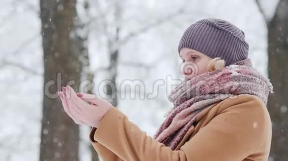 一个女人在她的手掌中捕捉雪花在冬天的到来中欢欣鼓舞视频的预览图