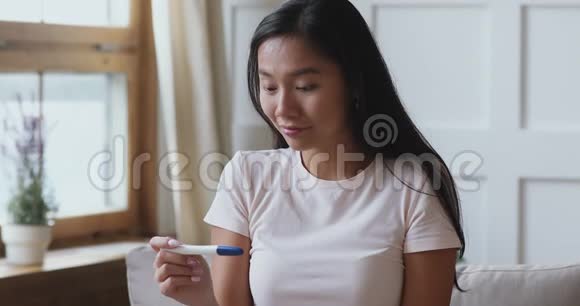 令人兴奋的年轻亚裔妇女在家中进行阳性妊娠试验视频的预览图