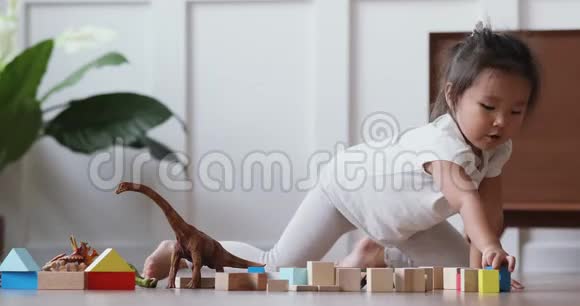 可爱的亚洲女孩玩玩具坐在温暖的地板上视频的预览图