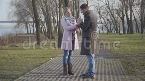 宽镜头年轻优雅的高加索男人温暖了城市公园里的老妇人的手年龄差的幸福夫妇视频的预览图