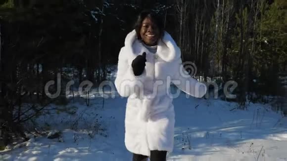 非洲裔美国女士微笑着沿着白雪皑皑的冬季公园奔跑视频的预览图