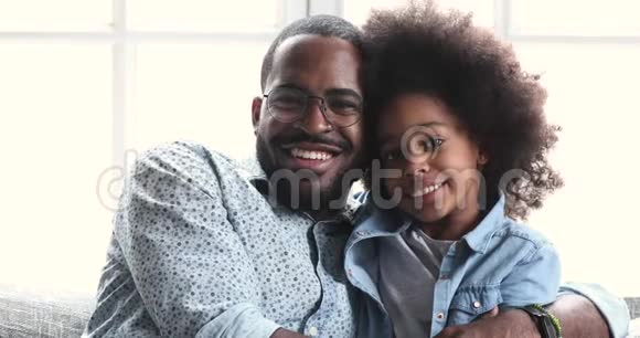 非洲爸爸和可爱的女儿看镜头笑拥抱视频的预览图