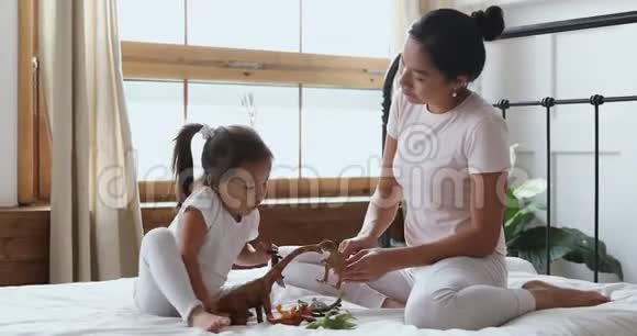 亚洲妈妈和小女儿玩玩具坐在床上视频的预览图