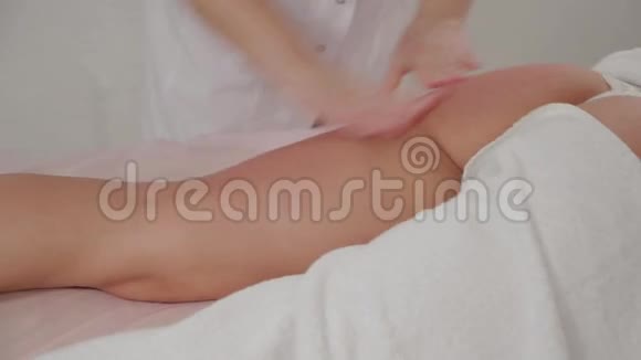女性按摩治疗师在按摩室里按摩一个年轻女孩的腿视频的预览图
