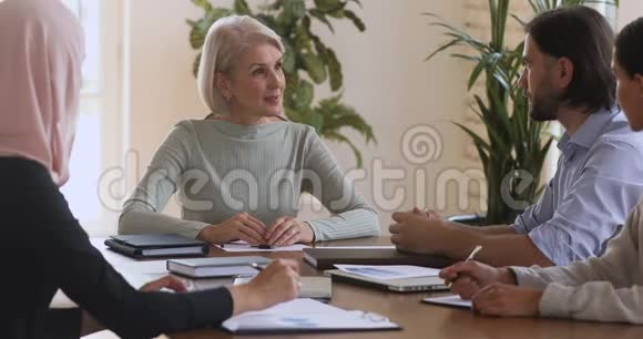 成熟的女性公司领导与团队会议的男性伙伴握手视频的预览图
