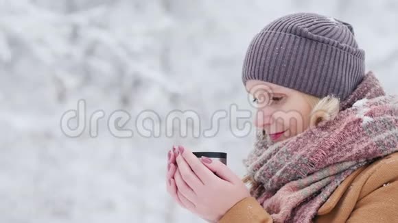 一个女人在冬天的森林里喝热茶视频的预览图