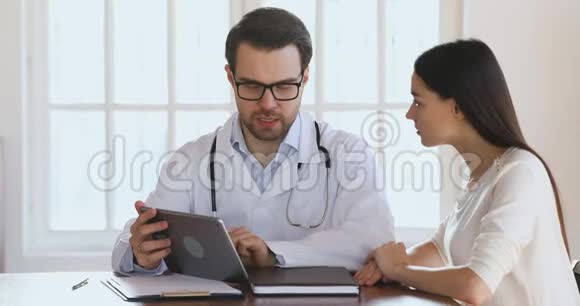 男性专业医生持数码片咨询年轻女性视频的预览图