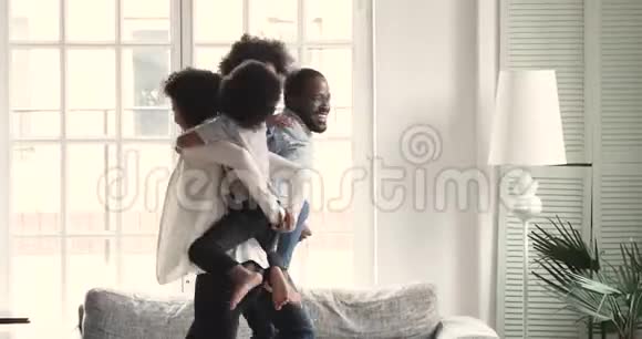 快乐活跃的非洲父母驮着孩子在客厅玩耍视频的预览图