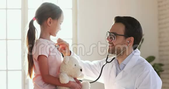 微笑男儿科医生拿着听诊器检查可爱的小女孩视频的预览图