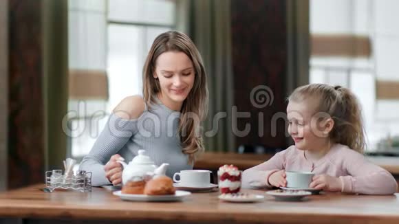 可爱的小女儿和微笑的母亲在咖啡馆享受家庭早餐中型摄影机视频的预览图