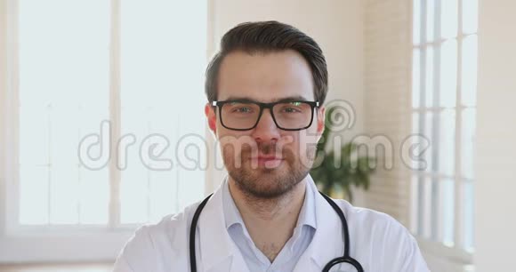 微笑男医生穿着白色制服看镜头特写镜头视频的预览图