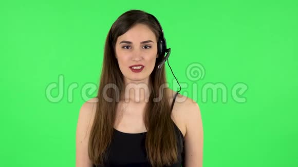 年轻女孩戴着耳机说话呼叫中心绿色屏幕视频的预览图