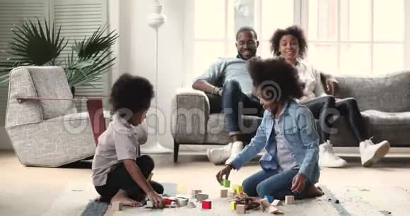 非洲孩子在地板上玩耍而父母则在沙发上放松视频的预览图