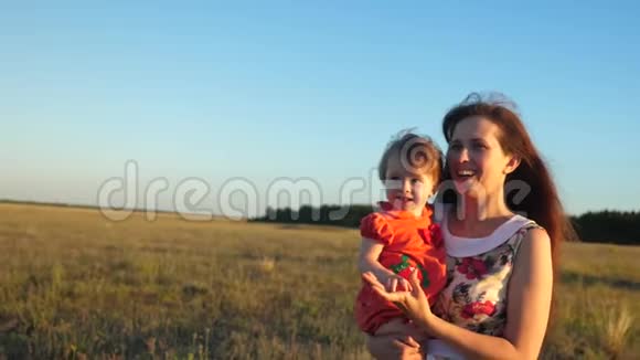 母亲和婴儿在大自然中行走快乐的妈妈抱着孩子散步妈妈和小女儿正沿着视频的预览图