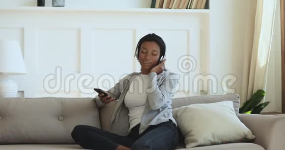 快乐的混血女人从移动应用程序中收听音乐曲目视频的预览图