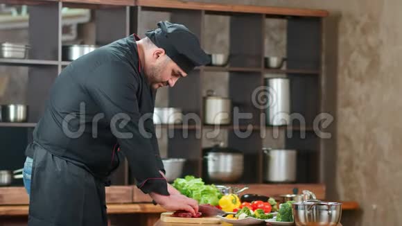 专注于男厨师在厨房的餐桌上统一切鲜肉中型摄影机视频的预览图