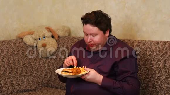 坐在沙发上吃汉堡和炸薯条的胖子视频的预览图