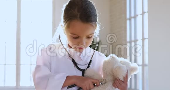 小女孩穿着医用制服拿着听诊器听玩具病人视频的预览图